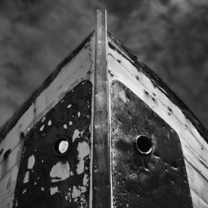 Dismissed white boat with iron planks and prow pointing at the sky