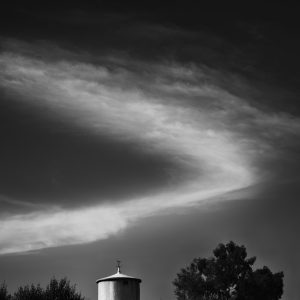 V-shaped cloud above round tower and trees