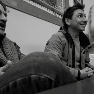 Two friends sitting at a table in a bar with glass in foreground