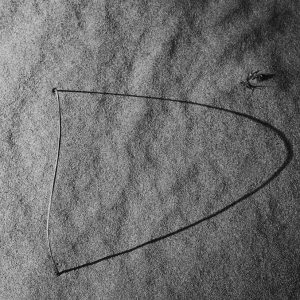 An arched straw projecting shadow on sand