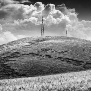 Two electricity pylons on hilltop with billowing clouds in background