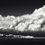 Storm clouds above the sunlit seaside town of Termoli, Italy.