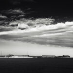 Triangular cloud pointing left against the wind above harbour.