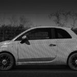 Lateral view of parked Fiat 500 car painted in houndstooth black&white pattern.