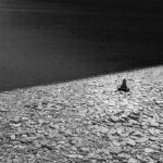 Stack of flat dark stones on beach of pale pebbles.