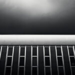Dark facade with vertical rows of metal windows and square white structure on top