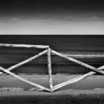 Wooden fence with crossed bars against sea.