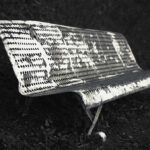 Metal bench with scorched white paint.